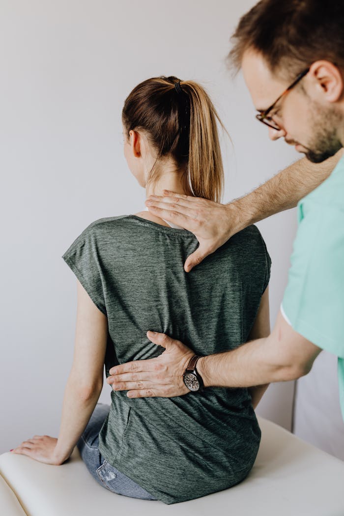 About A chiropractor examines a patient's spine in a clinical setting. Health care and rehabilitation focus.